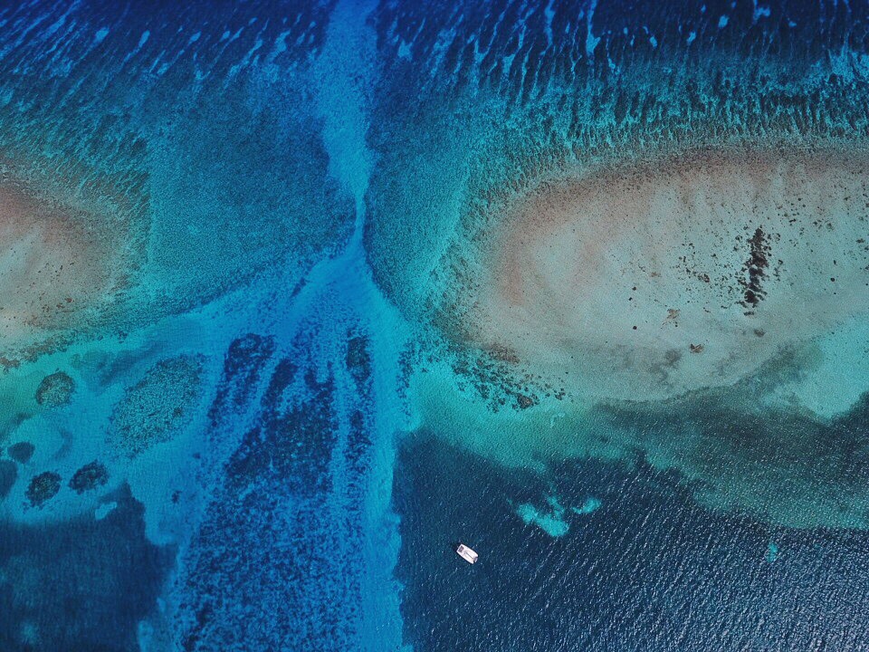Aerial photo of the Belize Barrier Reef near the Blue Hole featuring deep blue and turquoise coloured water 