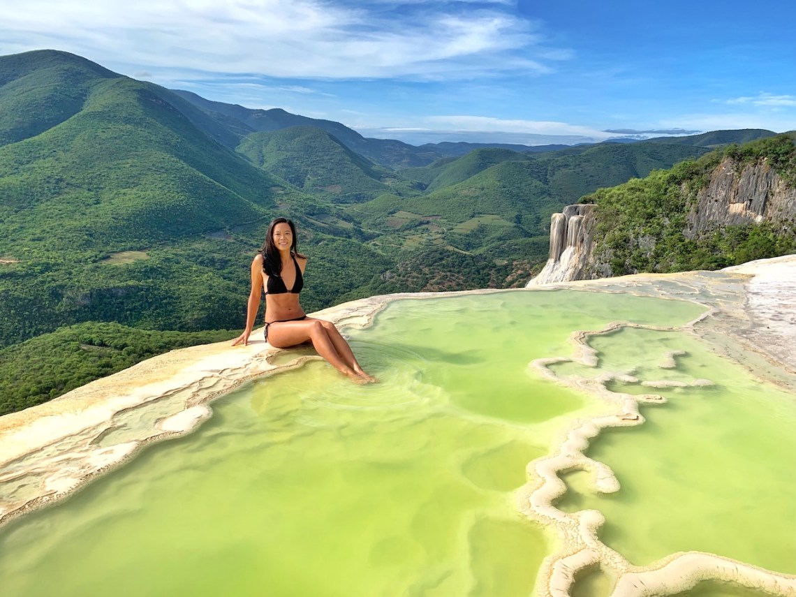 Woman sitting in water pools of Hierve el Agua with Sierra Madre mountain backdrop in the Oaxaca region of Mexico
